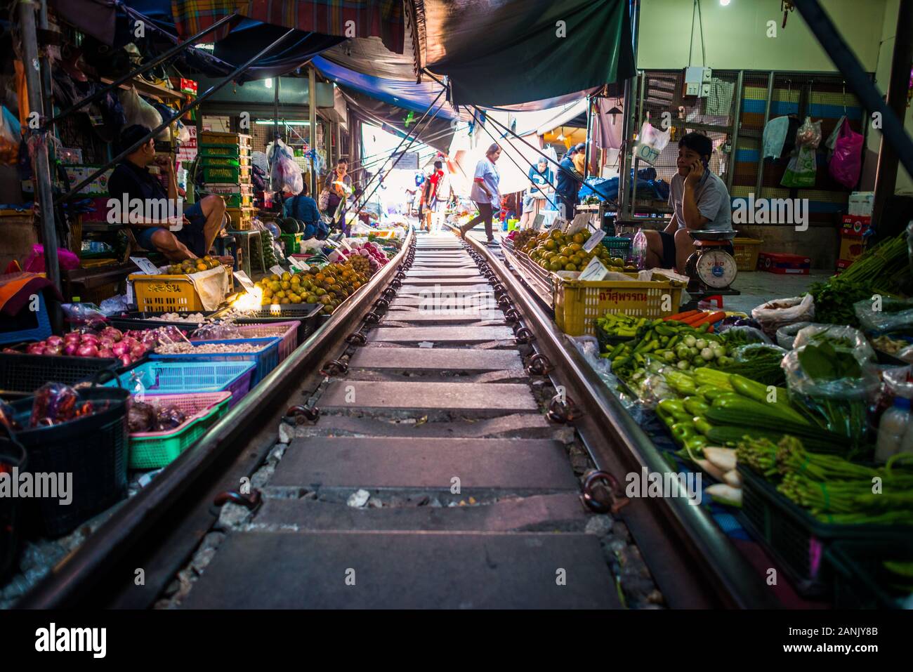 Mae Klong/Thailand-08December2019: Gare de Mae Klong avec voies et train passant par le marché quotidien avec des vendeurs vendant tout. Banque D'Images