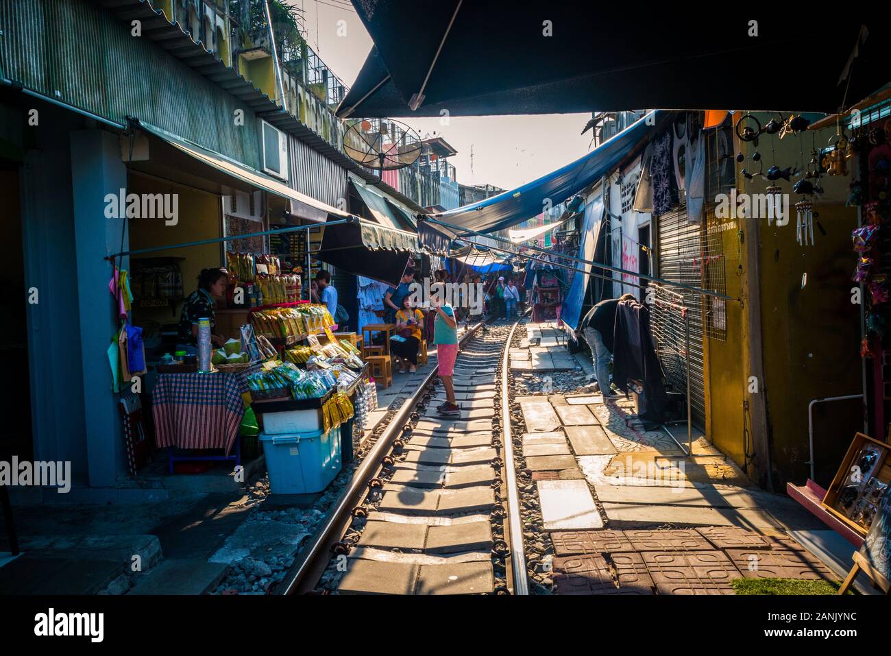 Mae Klong/Thailand-08December2019: Gare de Mae Klong avec voies et train passant par le marché quotidien avec des vendeurs vendant tout. Banque D'Images