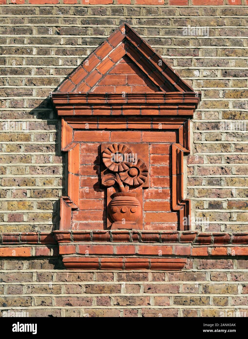 Tournesols en terre cuite sous un fronton décoratif sur le côté d'une maison à Bedford Park, Londres. Banque D'Images