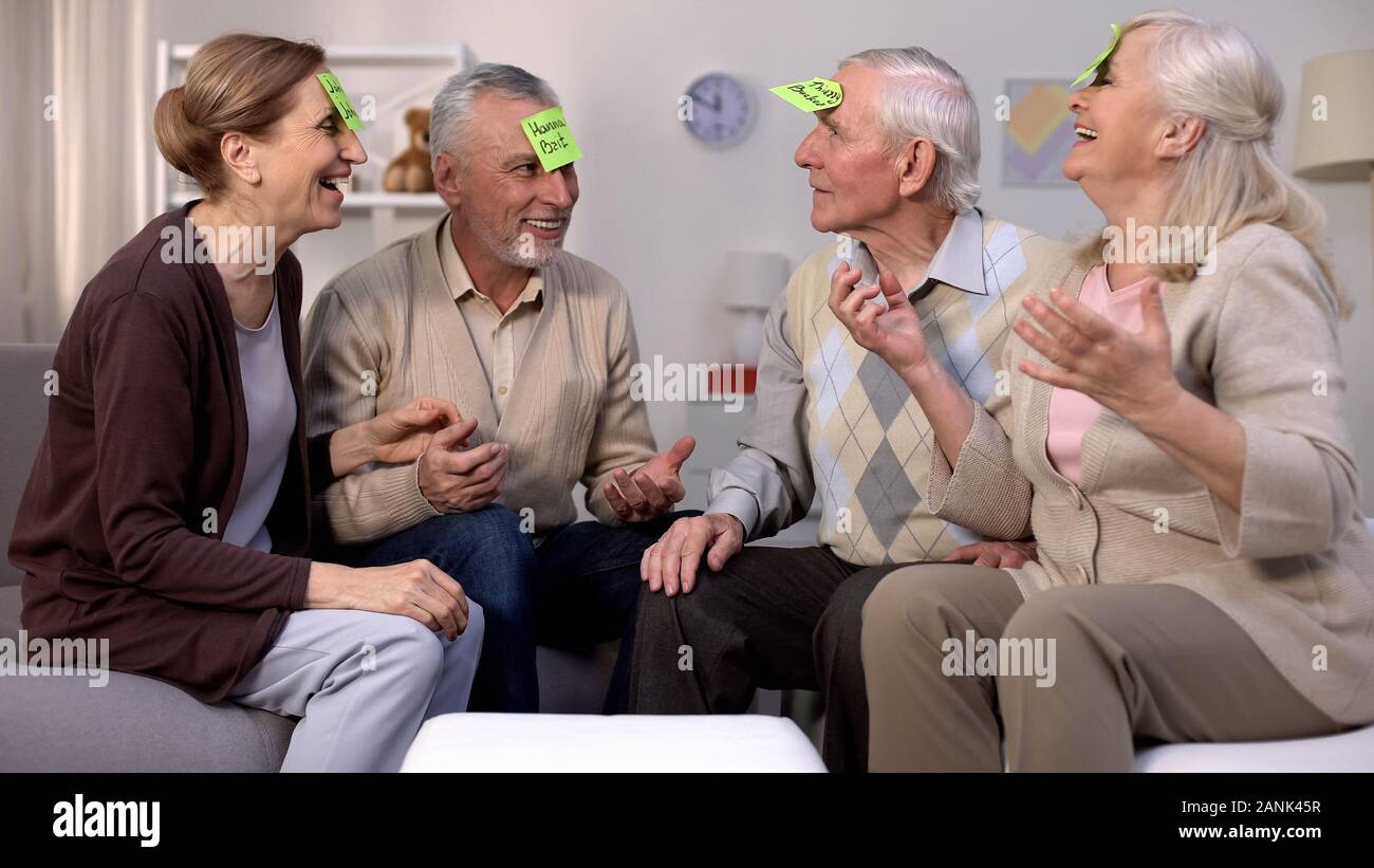 Les personnes âgées actives jouant le jeu qui suis-je assis en salle de séjour, loisirs Banque D'Images