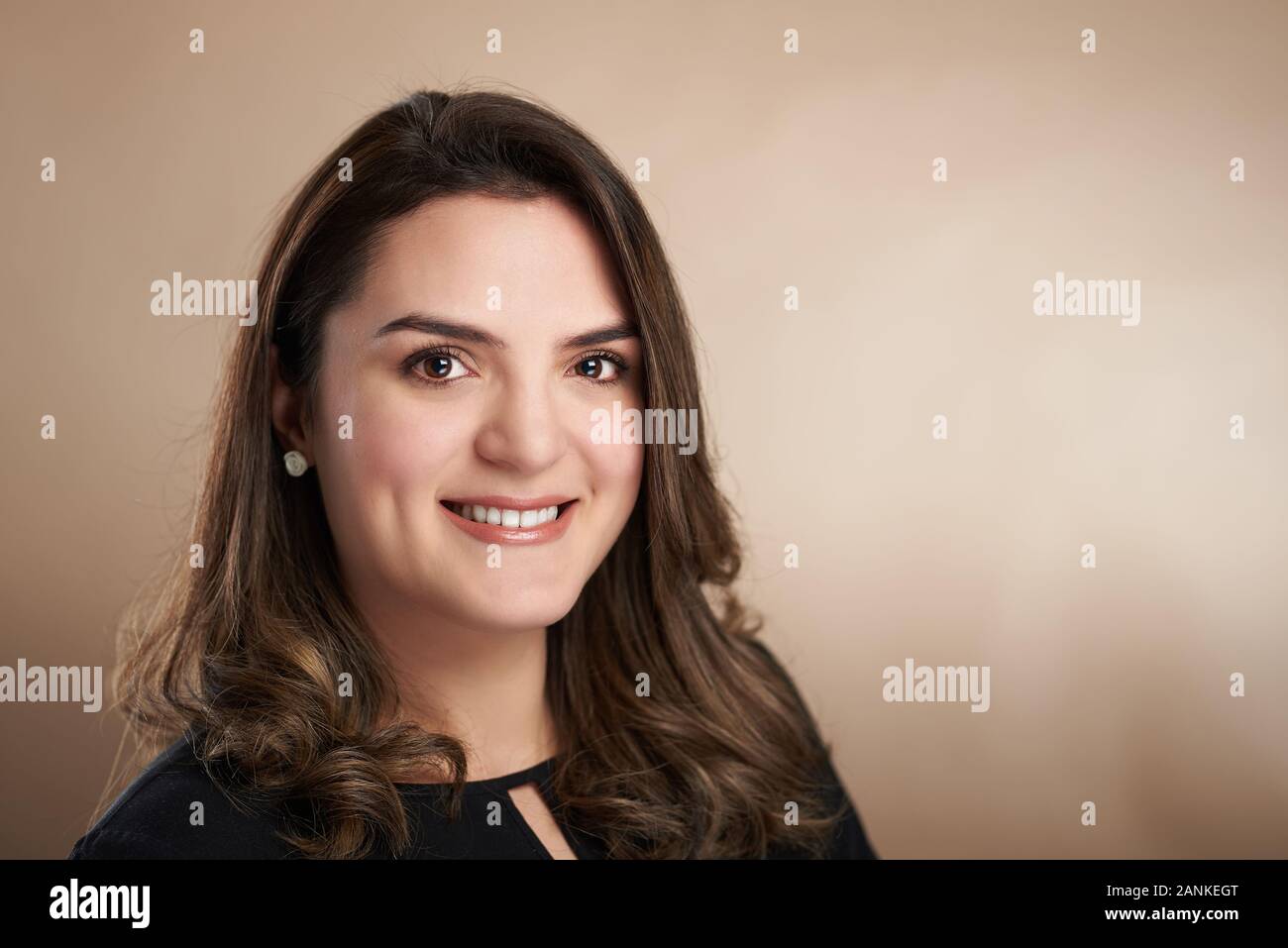 Portrait of smiling femme latine sur fond marron studio Banque D'Images