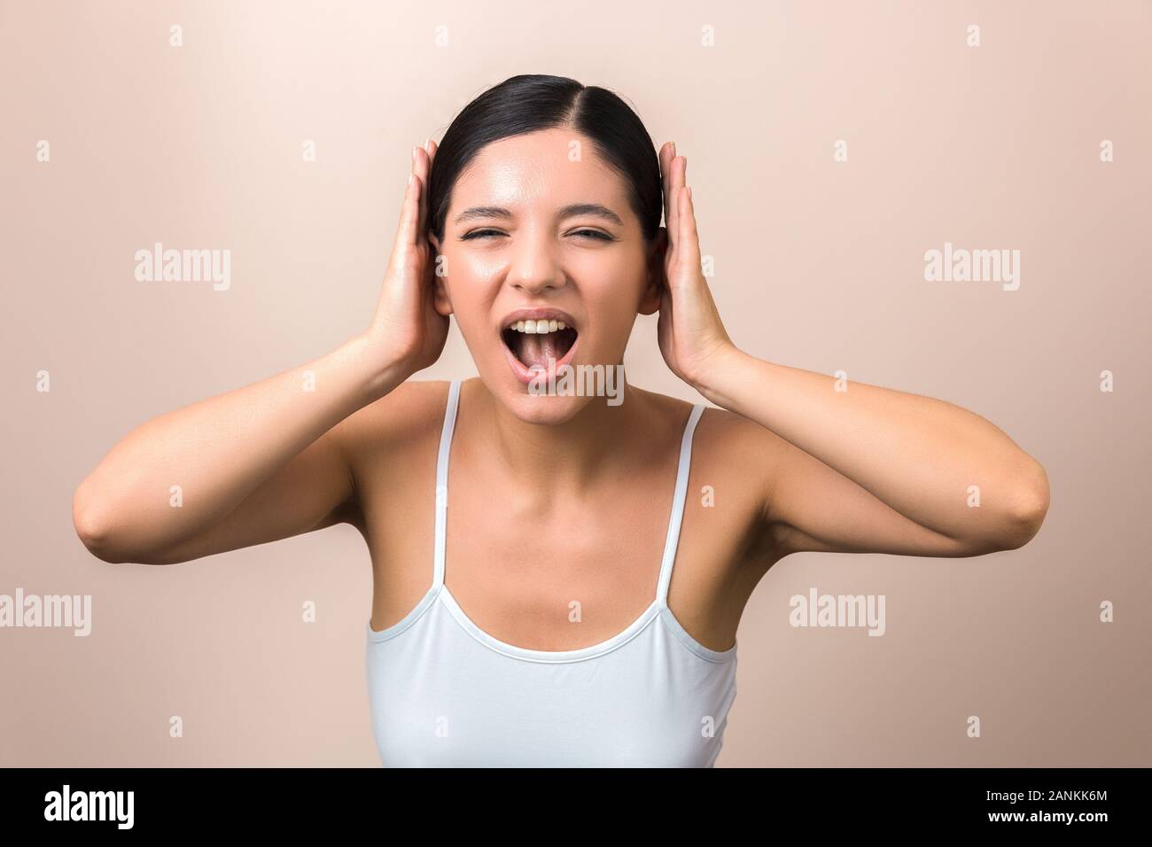 Belles femmes frustrées par le bruit des cris et couvrant ses oreilles Banque D'Images