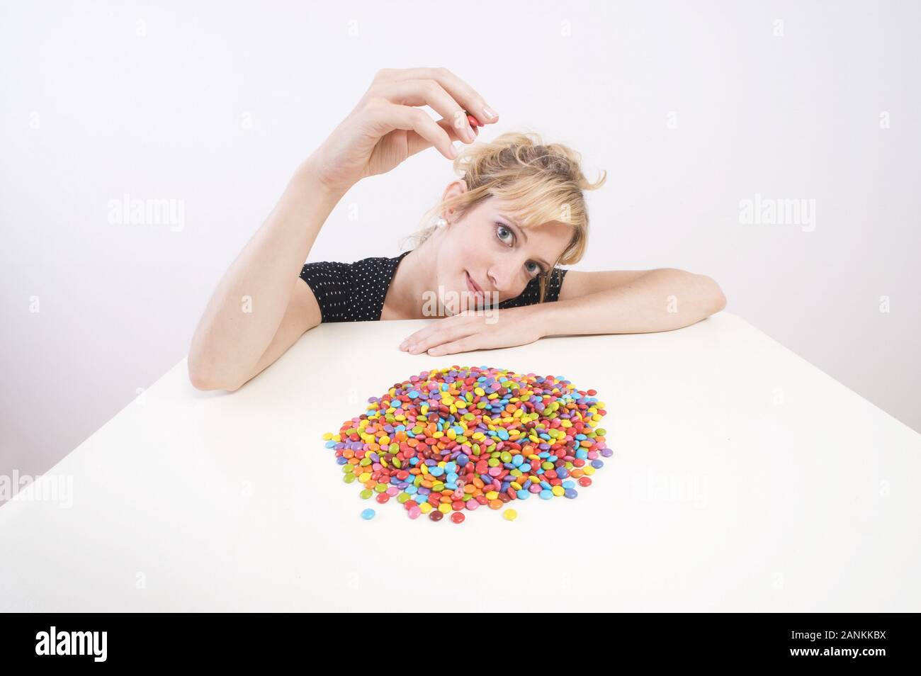 Junge Frau vor einer Schale mit Schokolinsen - Jeune femme à l'avant de la cuvette avec les lentilles au chocolat Banque D'Images