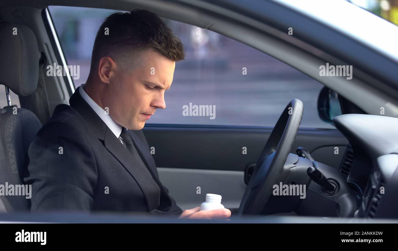 L'homme en costume d'affaires qui prennent des médicaments en voiture, risque d'effets secondaires, des vertiges Banque D'Images