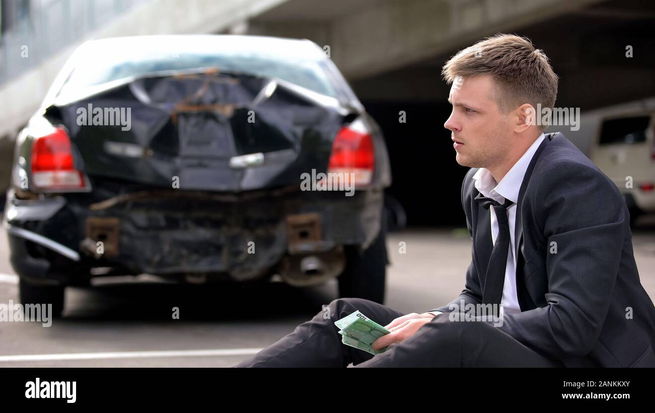 Le conducteur nerveux holding euro sur arrière-plan automatique, fracassé le paiement de dommages Banque D'Images