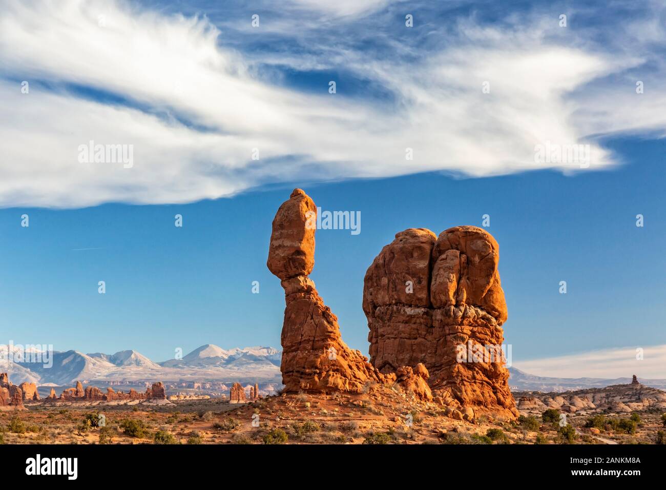 Des oiseaux comme les nuages vaporeux sur Balanced Rock emblématique contre la La Sal Mountain en parc national Arches dans Moab, Utah. Banque D'Images