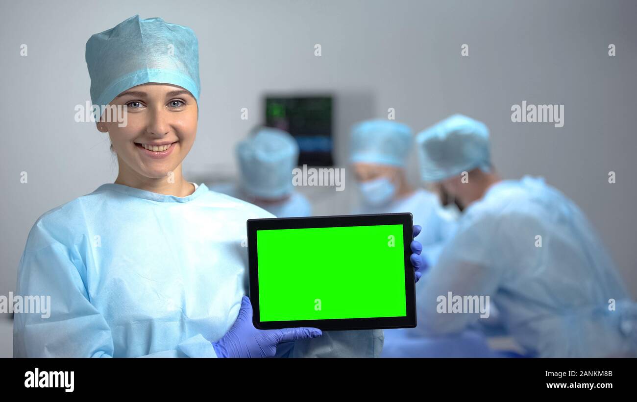 Smiling nurse holding tablet PC avec un écran vert lors de l'opération, annonce l'hôpital Banque D'Images