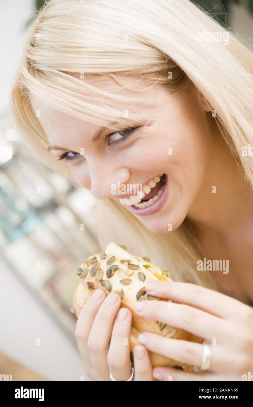 Fröhliche junge Frau hält ein Brötchen - Happy young woman holding pain Banque D'Images