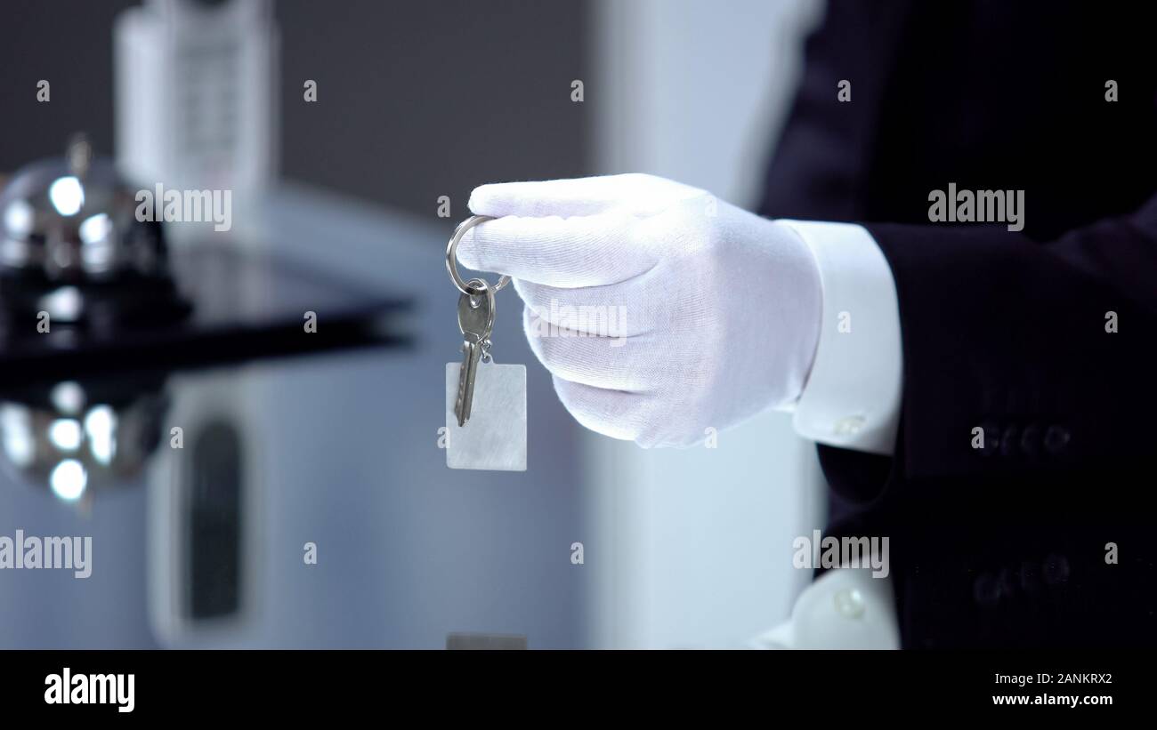 Homme de gant blanc clé donnant sur la chaîne, un service de haute qualité de l'hôtel de luxe Banque D'Images