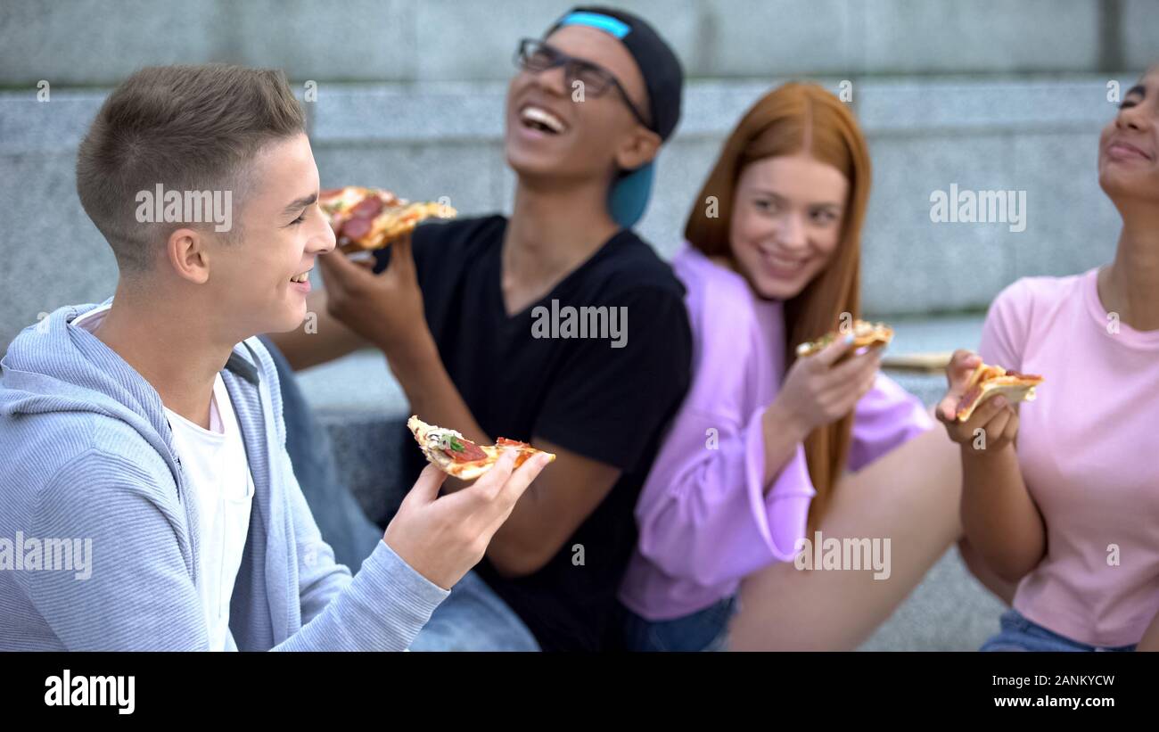 Groupe d'adolescents dans la bonne humeur rire sincèrement au cours de pizza, de l'amitié Banque D'Images