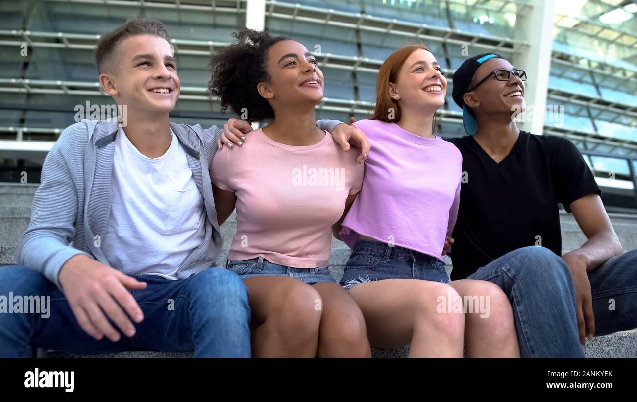 Cheerful woman hugging assis ensemble, stade multiracial students Banque D'Images