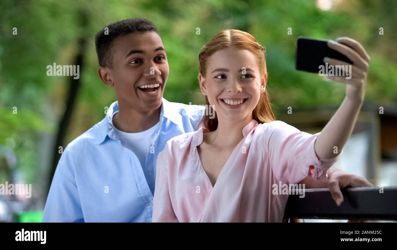 Smiling young couple having fun, faisant des photos sur l'appareil photo du smartphone selfies Banque D'Images