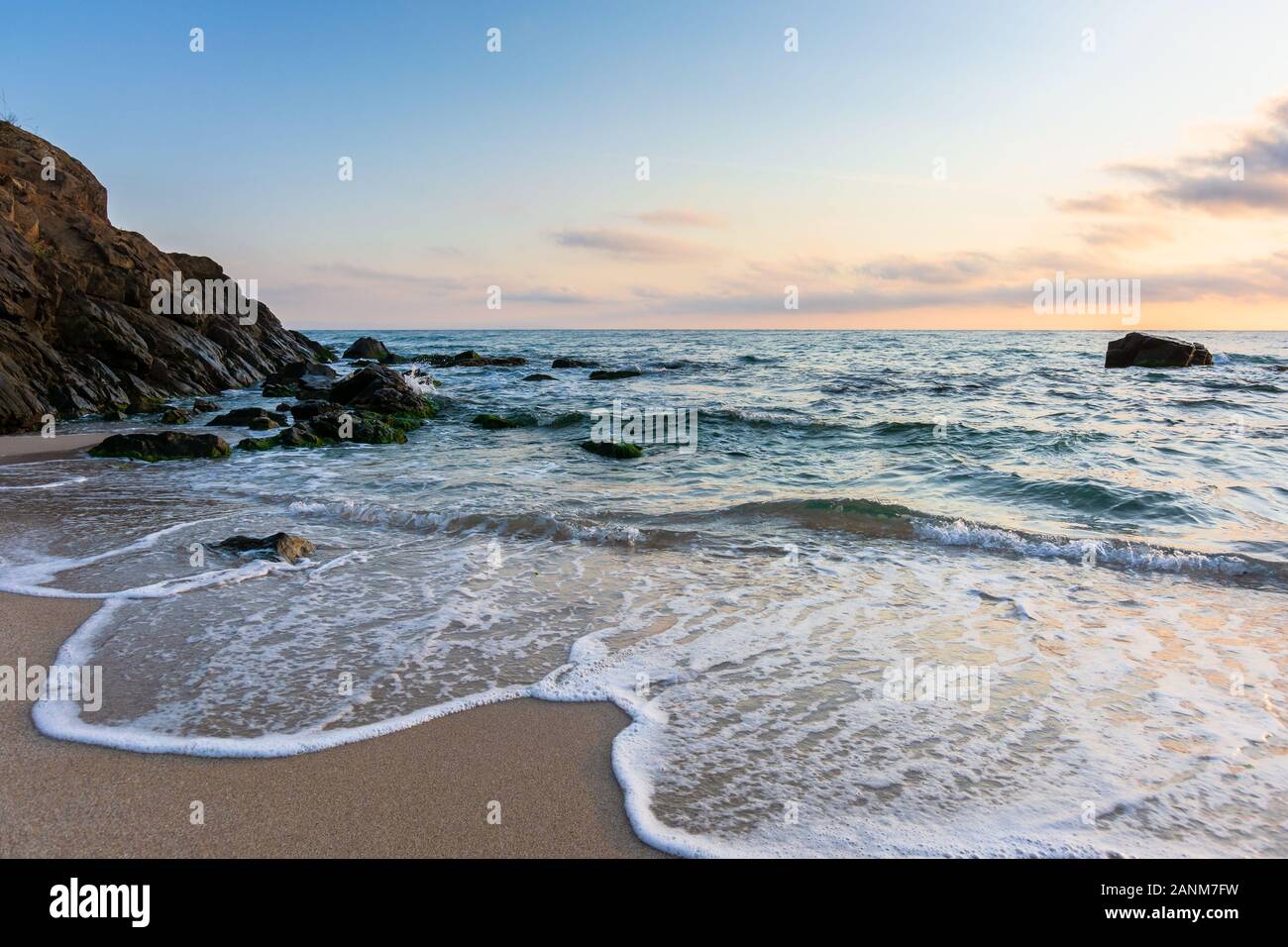 Lever de soleil sur la plage. été magnifique paysage. roches sur le sable. calme les vagues sur l'eau. Les nuages dans le ciel. Vue panoramique Banque D'Images