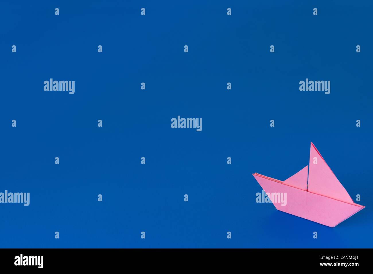 Origami rose bateau contre un arrière-plan peint bleu Banque D'Images