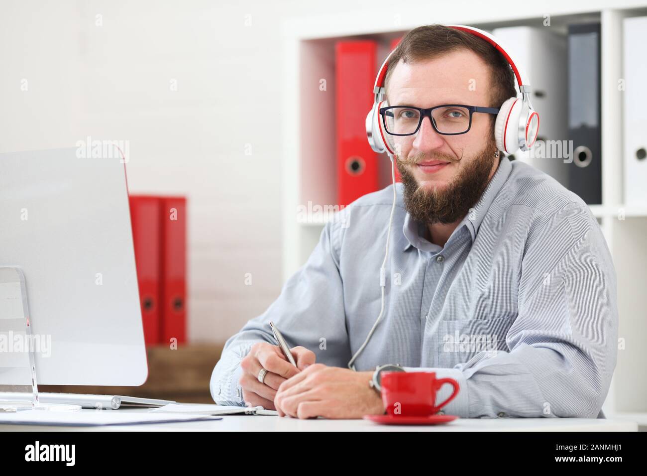 Un homme en casque d'écoute de la musique et apprend en ligne. Prend des notes sur un ordinateur portable et s'intéresse à l'appareil photo Banque D'Images