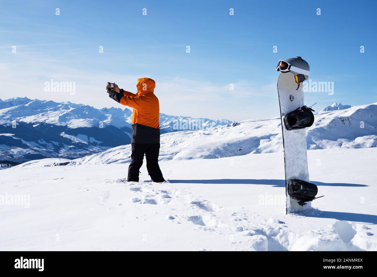 Homme avec photographie Téléphone sur Paysage de neige près de Snowboard et de sports d'hiver Accessoires Banque D'Images