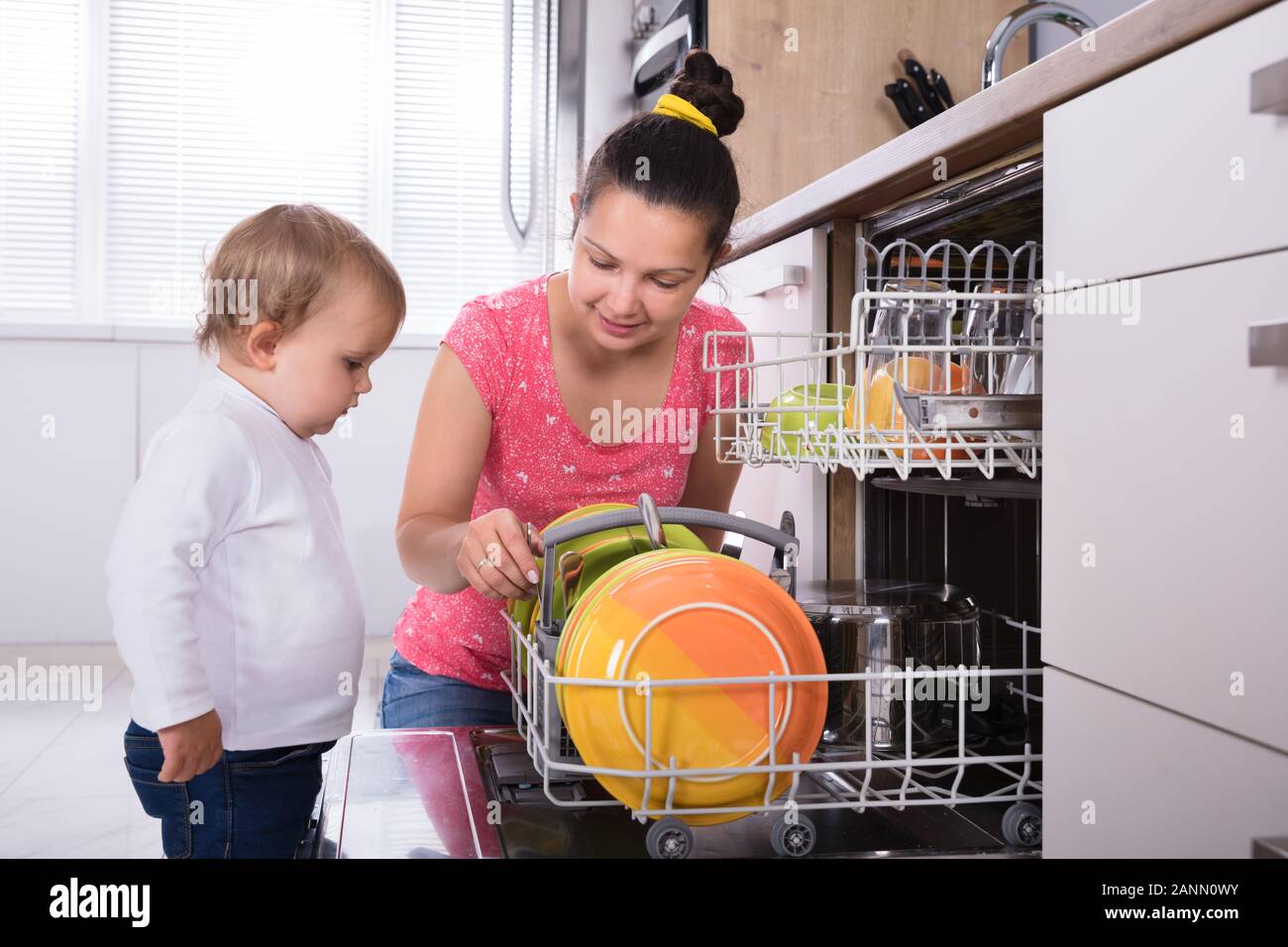 Petite fille aider sa mère pour décharger le lave-vaisselle Banque D'Images