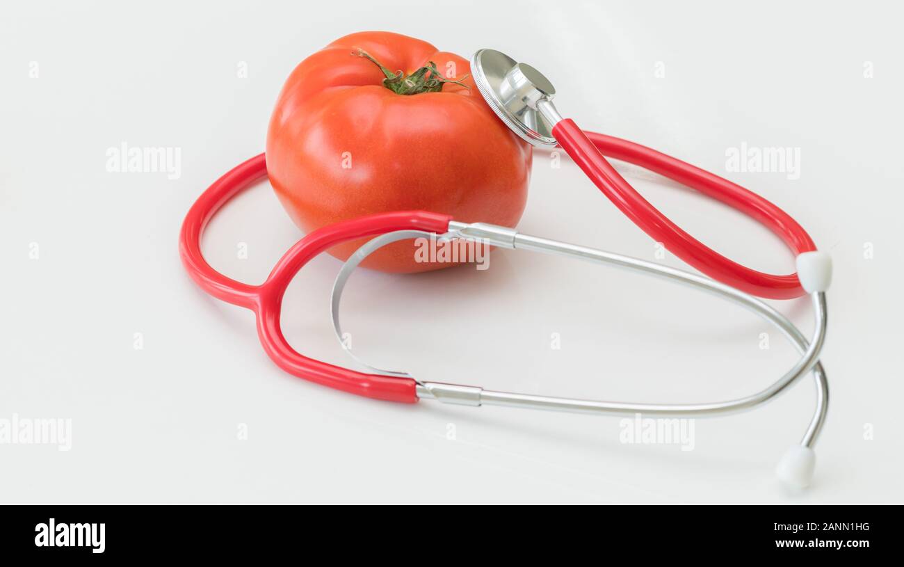 Concept d'aliments sains - tomate et médecin stéthoscope sur fonds blancs montrant les avantages de la vitamine et des nutriments de la tomate. Banque D'Images