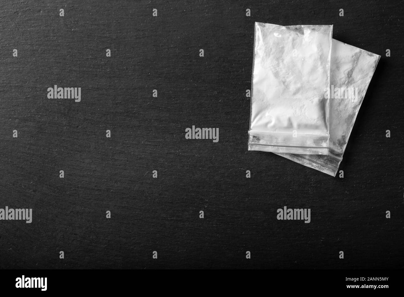 La poudre dans un sac en plastique sur un fond noir. Le trafic illégal des drogues. place pour le texte Banque D'Images