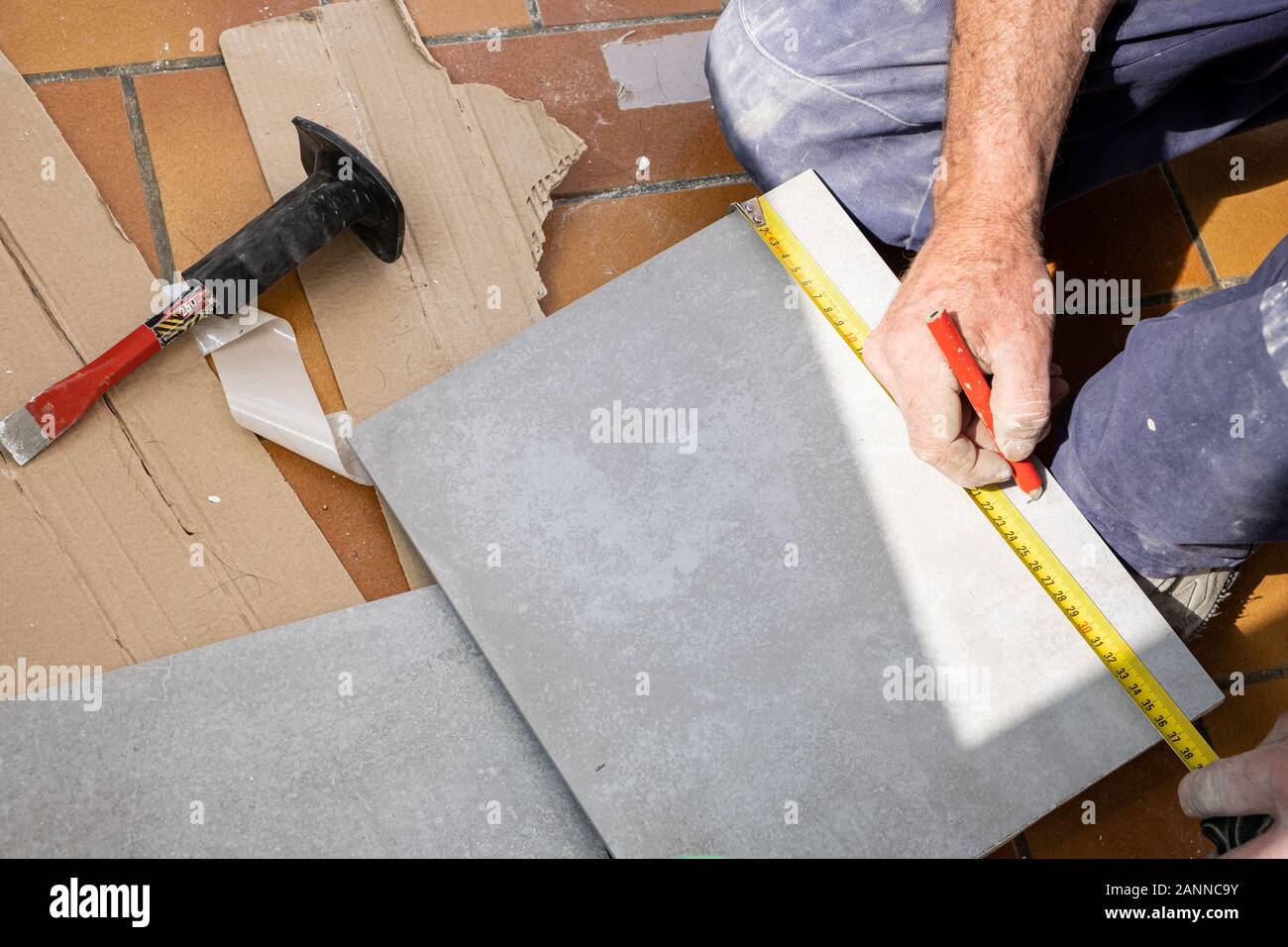 Le carreleur mesure les carreaux avant qu'elle coupe Banque D'Images