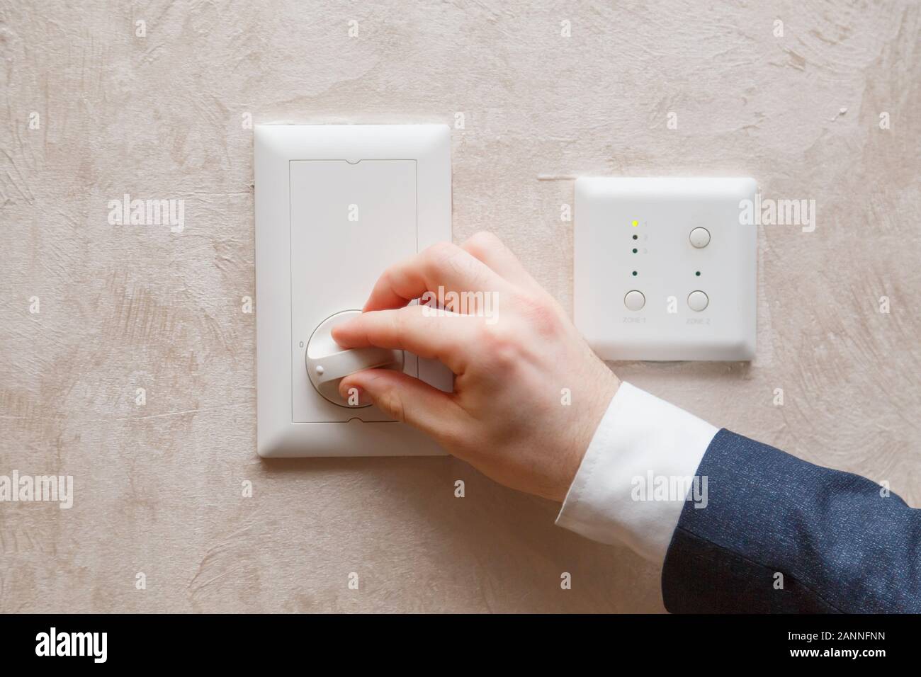 L'homme la régulation de la température sur le thermostat contrôleur de climatisation sur le mur Banque D'Images