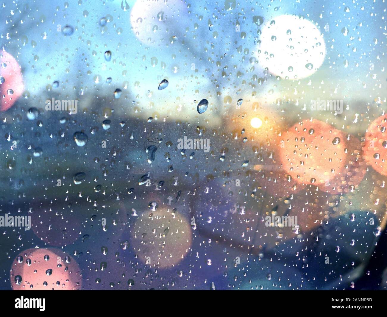 Fenêtre de voiture avec des gouttes de pluie sur humide journée d'hiver au coucher du soleil. Banque D'Images