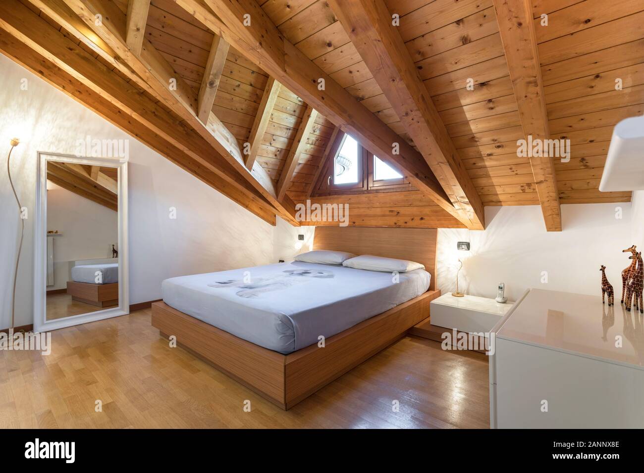 Intérieur d'une chambre italienne confortable avec parquet et plafond avec poutres apparentes et fenêtre en plein-ciel. Banque D'Images