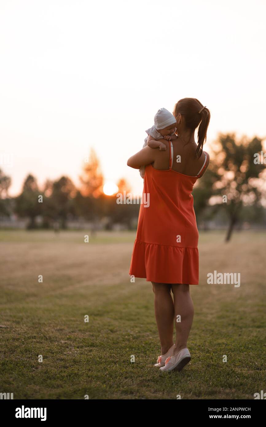Jeune Mere Holding Et Jouer Avec Son Bebe Garcon Enfant Dans City Park Port Permanent Robe Rouge Vif Fils Porte Bouchon Blanc Les Valeurs Familiales Au Chaud Photo Stock Alamy