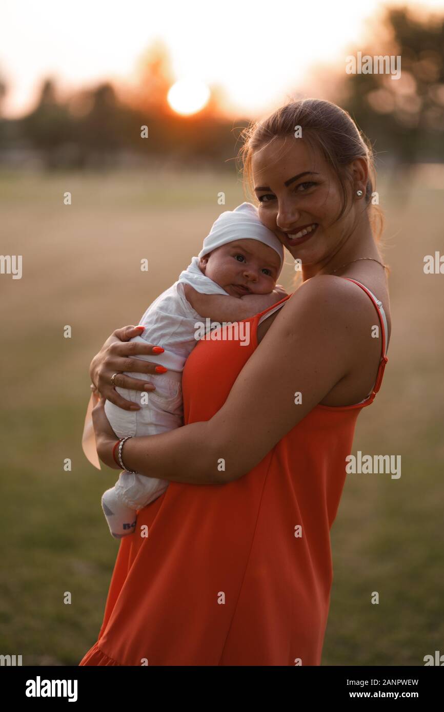 Jeune Mere Holding Et Jouer Avec Son Bebe Garcon Enfant Dans City Park Port Permanent Robe Rouge Vif Fils Porte Bouchon Blanc Les Valeurs Familiales Au Chaud Photo Stock Alamy