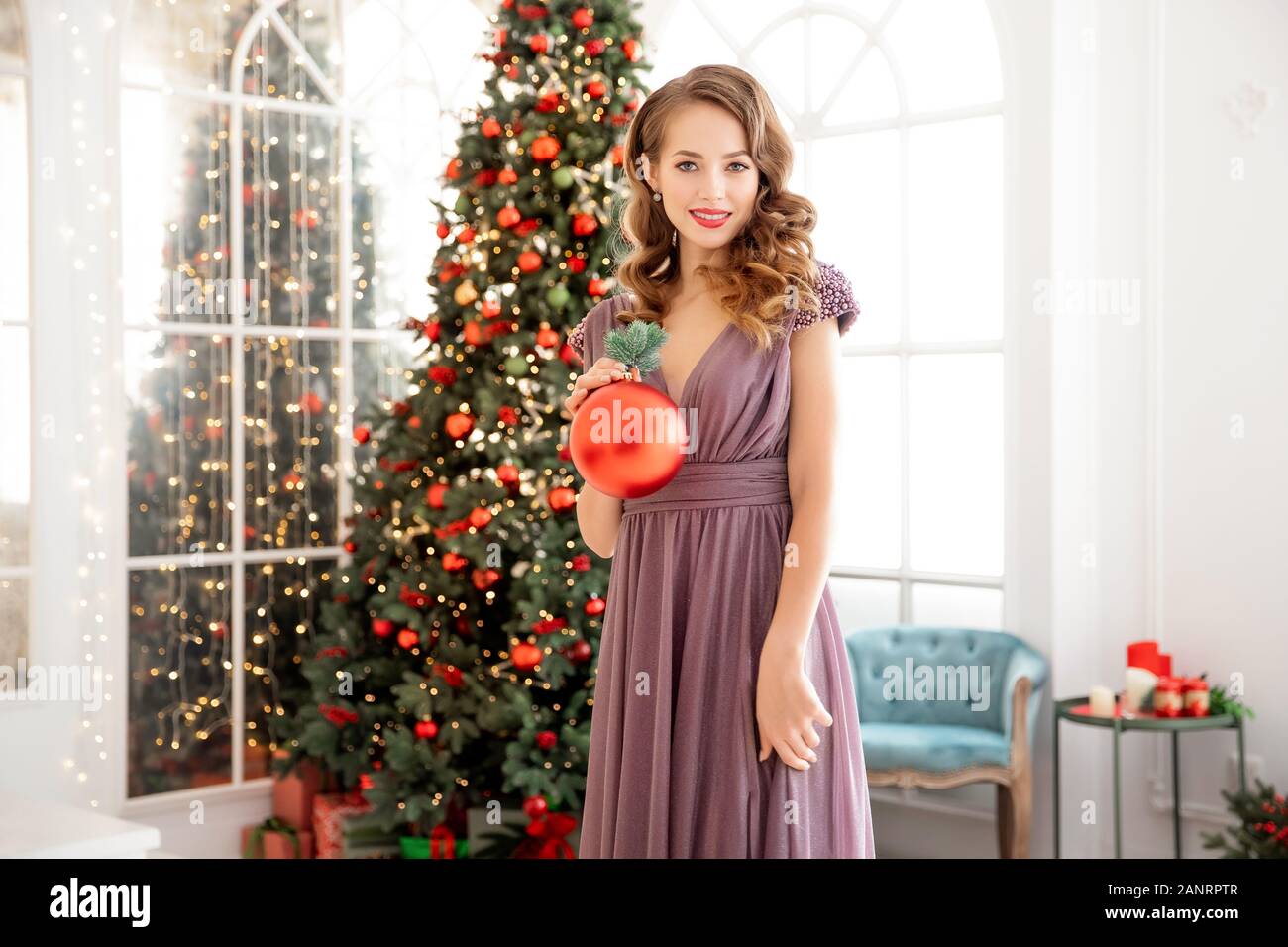 Belle jeune femme avec le maquillage et la coiffure de soirée robe de  sourires et la décoration de sapin de Noël pour les fêtes, couleur rouge  Photo Stock - Alamy
