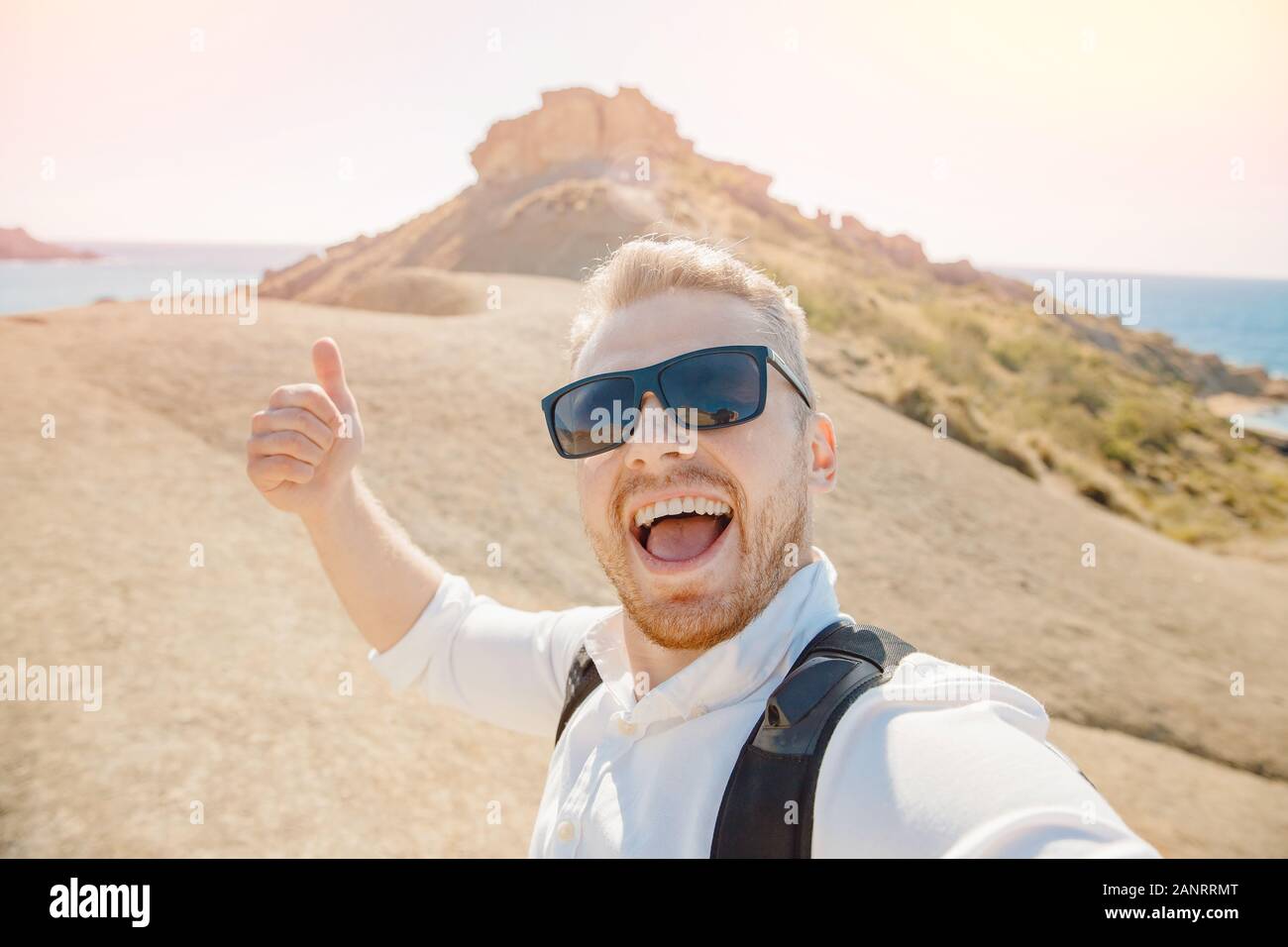 Les voyageurs prennent mâle photo selfies sur fond bleu mer, plage de sable  fin de lunettes de soleil et avec sac à dos. Concept de voyage. Baie d'Or  Malte Photo Stock -