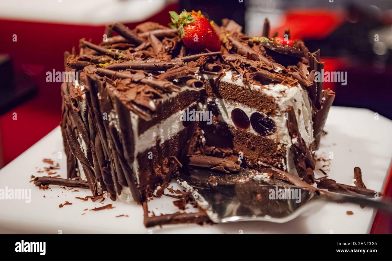 L'accent sélective fait maison fraîchement préparés en couches délicieux gâteau au chocolat décoré avec des fraises et du chocolat râpé. Dans la restauration, en bonne santé Banque D'Images