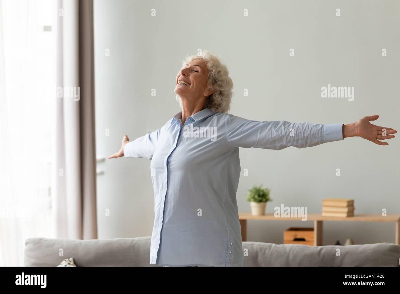 Happy smiling woman standing with arms outstretched at home Banque D'Images