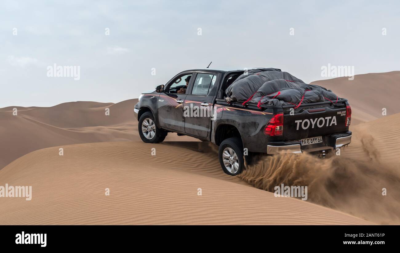 toyota hulux revo escalade une dune de sable éclaboussant des sables autour dans dasht e lut ou sahara désert Banque D'Images