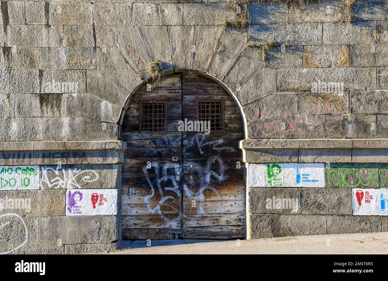 Close-up de la porte en bois d'un vieux hangar à bateaux sur la banque du fleuve Po (Murazzi) avec des pochoirs de graffiti sur le mur de pierre, Turin, Piémont, Italie Banque D'Images