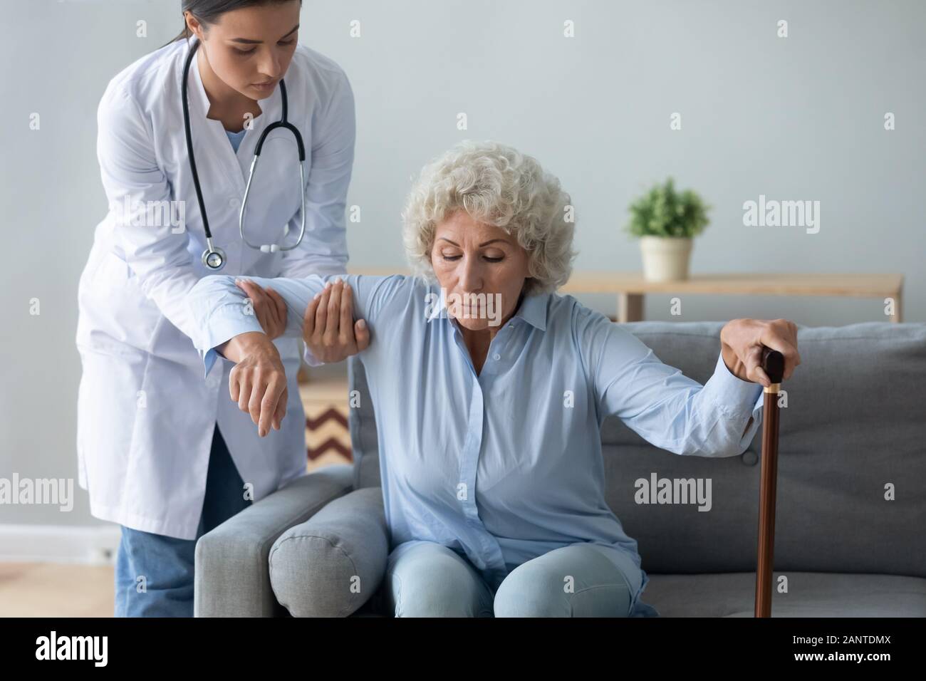 Aide infirmière femme plus âgée avec canne de se lever Banque D'Images