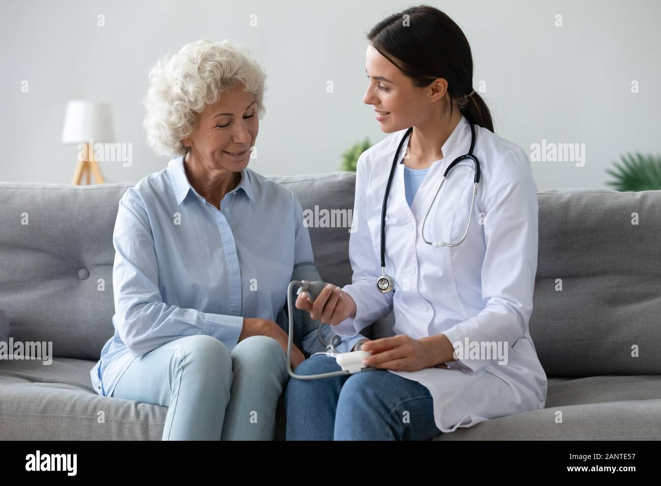 Friendly médecin femme plus âgée contrôle la pression artérielle à la maison Banque D'Images