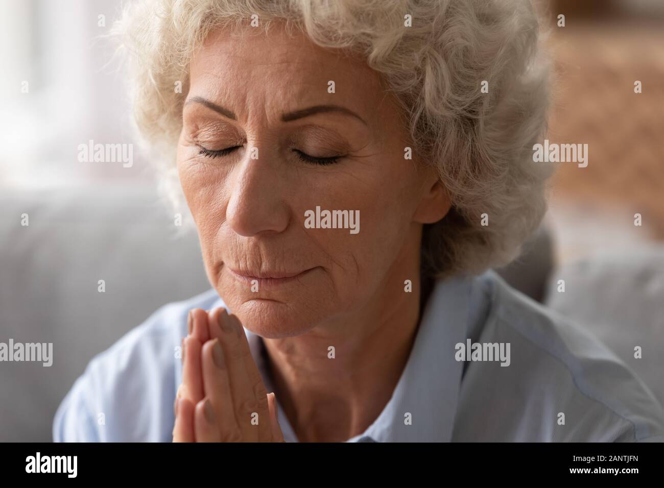 Close up femme plus âgée avec les yeux fermés en priant avec espoir Banque D'Images