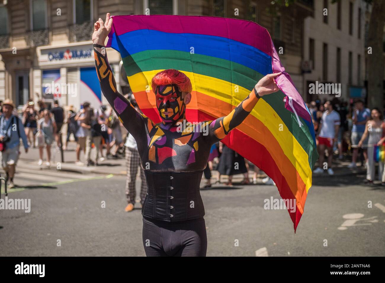 29 Juin 2019, Paris, France. Gay Pride Parade Day. Jeune homme tenant un drapeau regardant la caméra . Son visage et son corps sont peints ! Beau design Banque D'Images