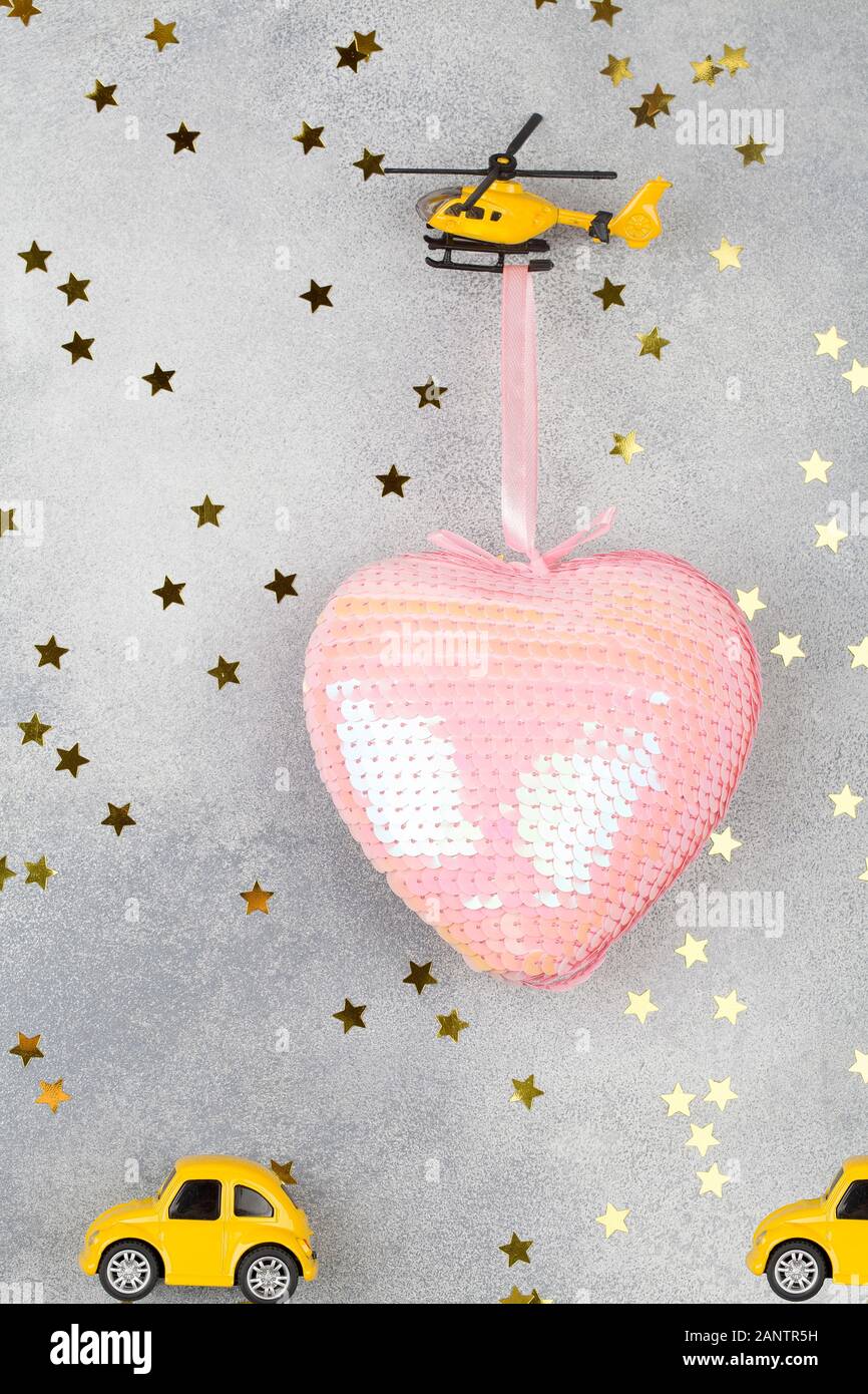 un petit hélicoptère porte un grand coeur rose et de petites voitures jaunes sur fond bleu avec des étoiles. Arrière-plan de la Saint Valentin. Élément de conception pour le message d'accueil CA Banque D'Images un petit hélicoptère porte un grand coeur rose et de petites voitures jaunes sur fond bleu avec des étoiles. Arrière-plan de la Saint Valentin. Élément de conception pour le message d'accueil CA Banque D'Images