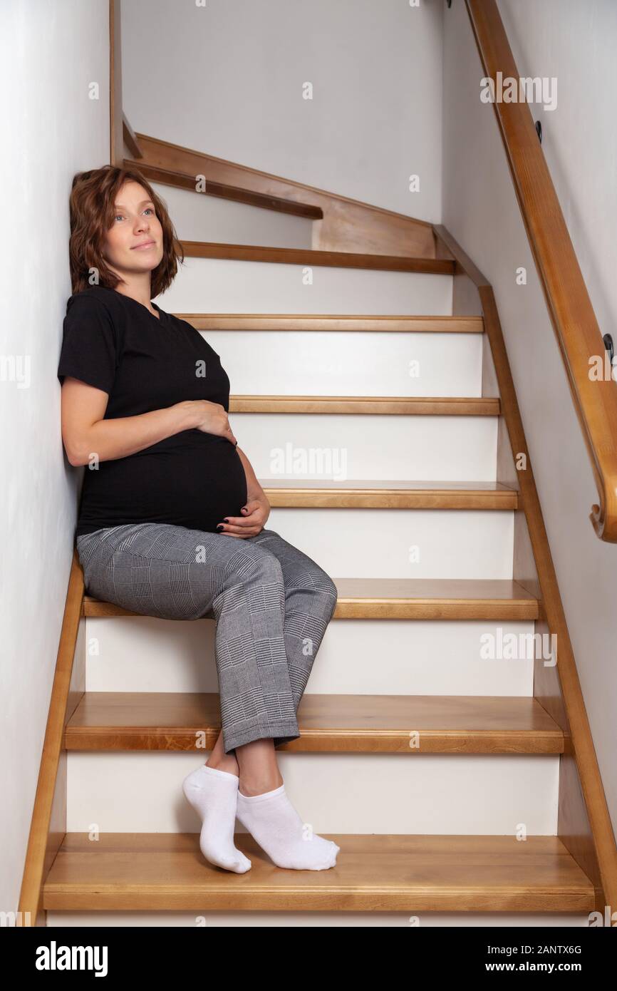 Femme enceinte se sentir heureux à la maison tout en prenant soin de son enfant. La jeune mère prévoyante holding baby in pregnant belly. Voiture prénatal maternité Banque D'Images