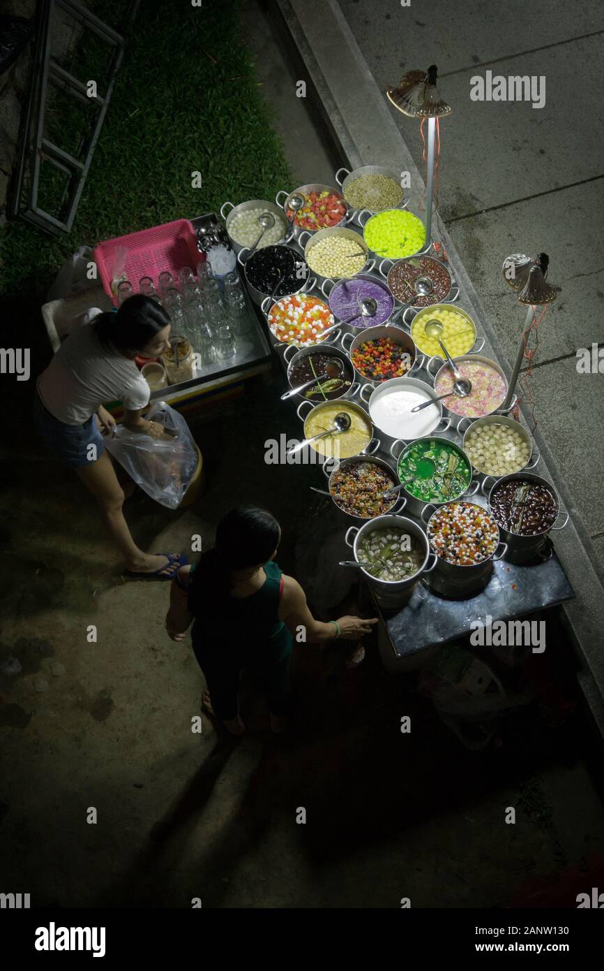 Une voiturette alimentaire de rue vendant des bonbons à Hue, au Vietnam. Photo prise dans la soirée du pont au-dessus. Photographie grand angle. Banque D'Images