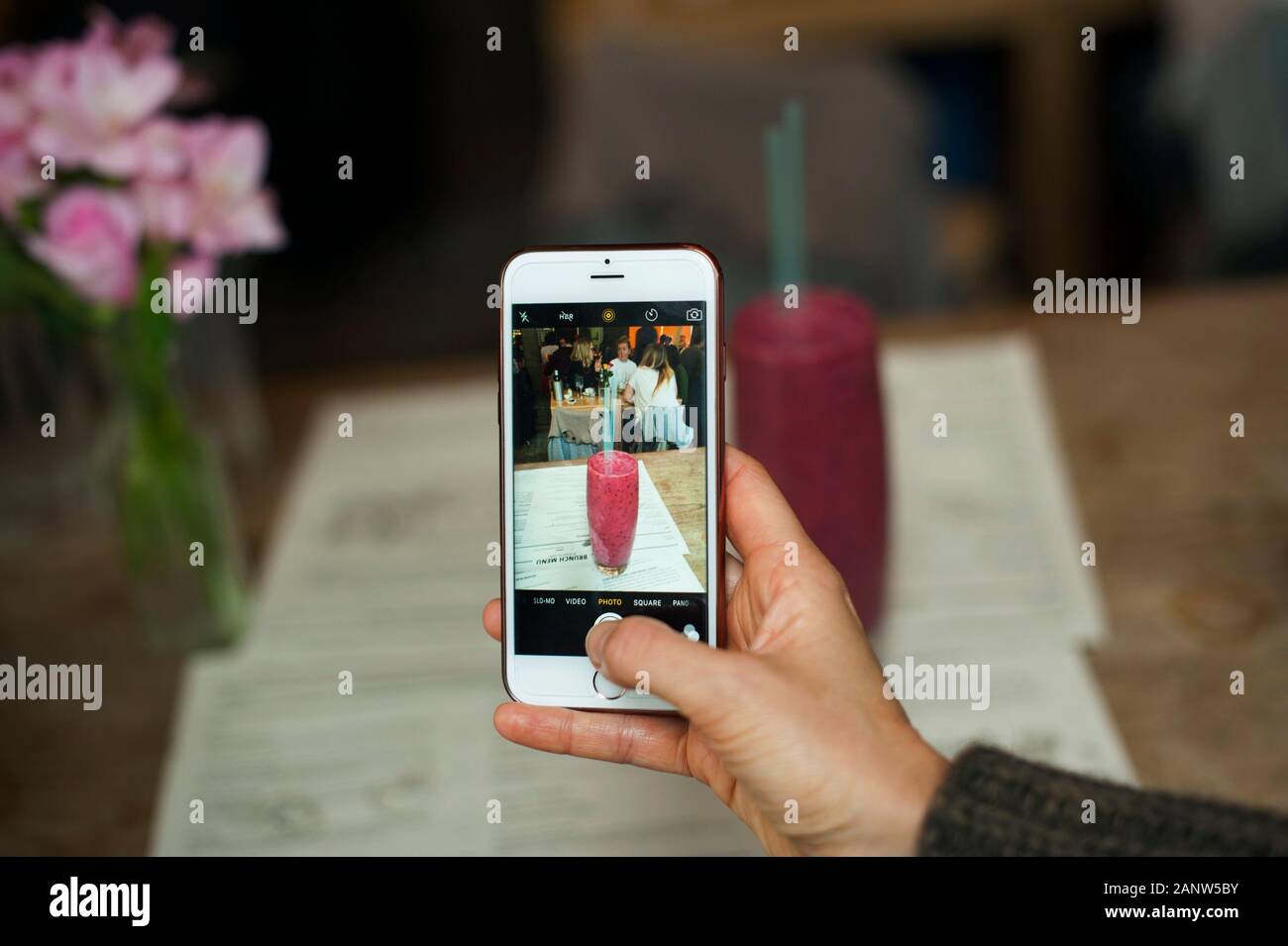 Main féminine prenant une photo d'un smoothie aux baies rouges au restaurant, à l'intérieur. RF mode de vie sain, fruit / végétalien concept. Londres, Royaume-Uni Banque D'Images