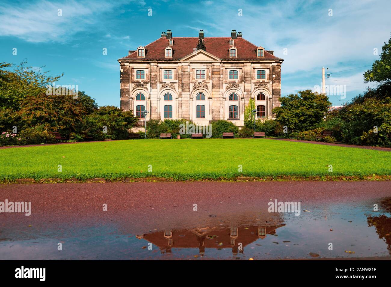 Vieille maison avec pelouse verte à Dresde, Allemagne. Flaque d'eau avec reflet en premier plan et bleu ciel nuageux en arrière-plan Banque D'Images