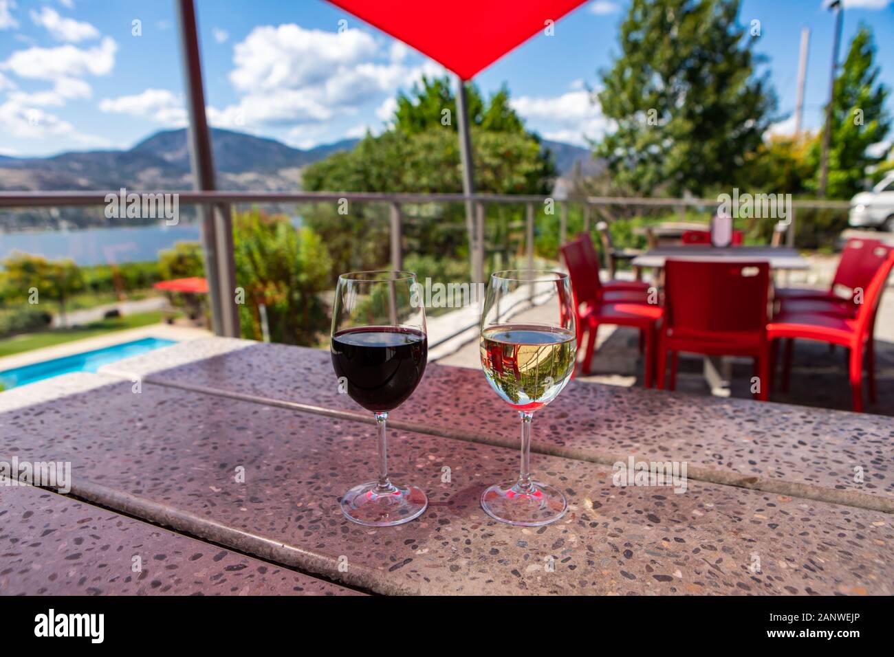 Vin rouge et vin blanc verres selective focus, sur table en terrazzo restaurant patio, salle de dégustation cave terrasse avec vue sur le lac Okanagan Banque D'Images