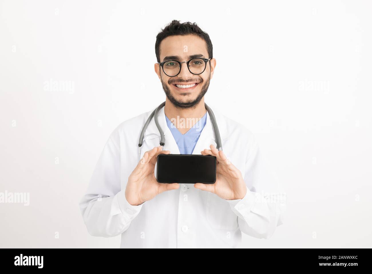 Cheerful young doctor avec dents sourire vous photographier sur smartphone Banque D'Images