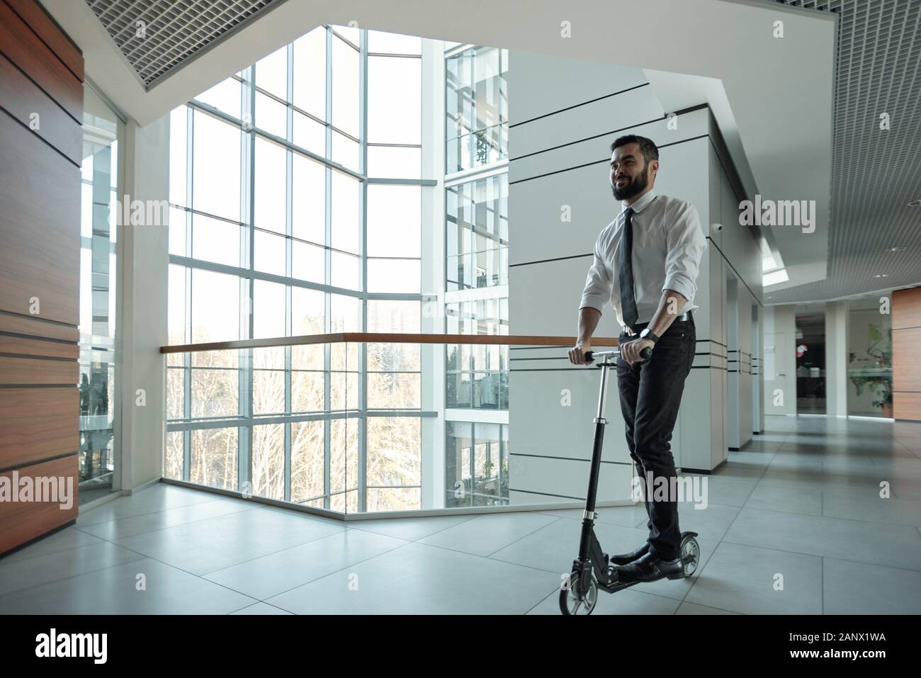 Jeune homme barbu d'avancer en se tenant sur le scooter Banque D'Images