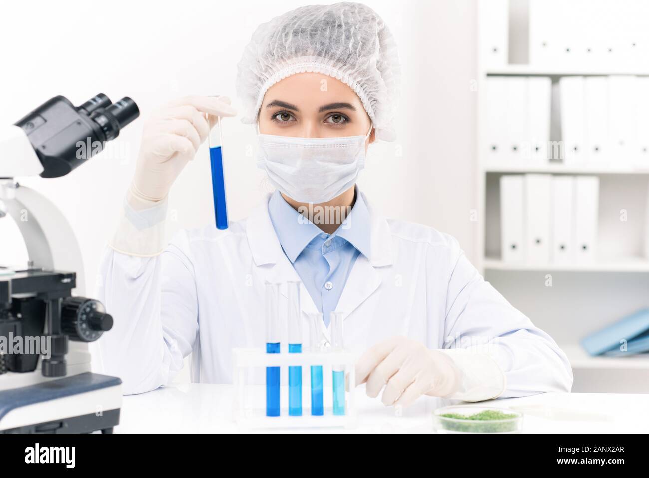 Jeune femme travailleur de laboratoire travaillant avec des substances liquides en flacons Banque D'Images