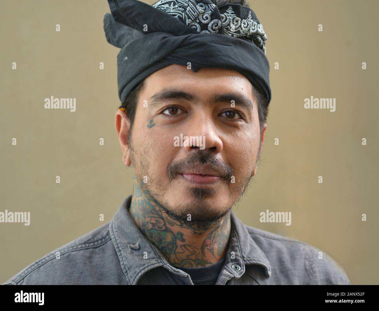 Beau artiste balinais tatouage avec cou tatoué porte un udang traditionnel et pose pour l'appareil photo. Banque D'Images