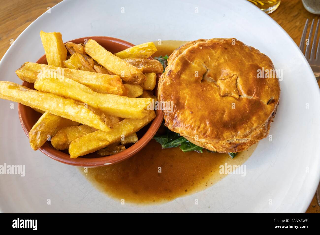 Copieux typique et savoureux repas au pub britannique : sex pâté à la viande en sauce servi avec un bol de golden fried chips chunky sur une plaque blanche chine Banque D'Images